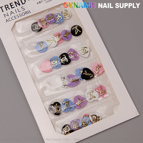 A pack of LV logo heart-shaped resin nail charms by Dynamic Nail Supply in black, white, pink, blue, and purple.