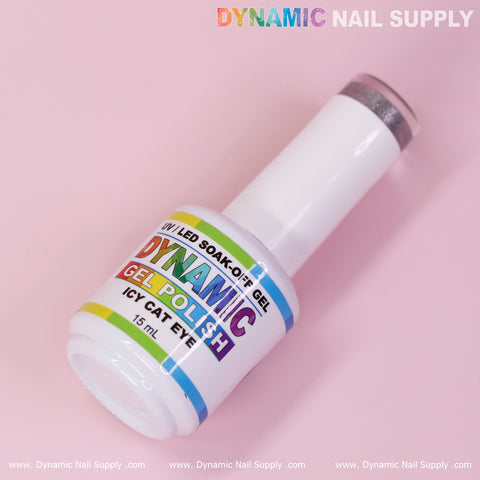 A bottle of Icy Cat Eye Gel - Reflective Magnetic Silver Shimmery Gel Polish, under the Dynamic Nail Supply brand, displays rainbow-gradient text on a sleek white bottle capped with a reflective magnetic silver tip. Set against a pastel pink backdrop, the label prominently features "Dynamic Nail Supply" at both the top and bottom edges.