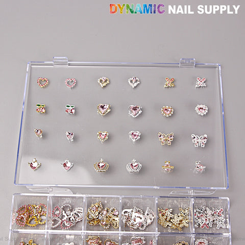 A clear case holds Dynamic Nail Supplys Pink Silver Gold Heart Shape Cherry Crown Planet Charm Set for nail art DIY.
