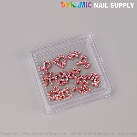 A clear case displays 12 pcs Pink Rhinestone Zodiac Sign Charms Nail Art DIY Accessories on a gray surface.