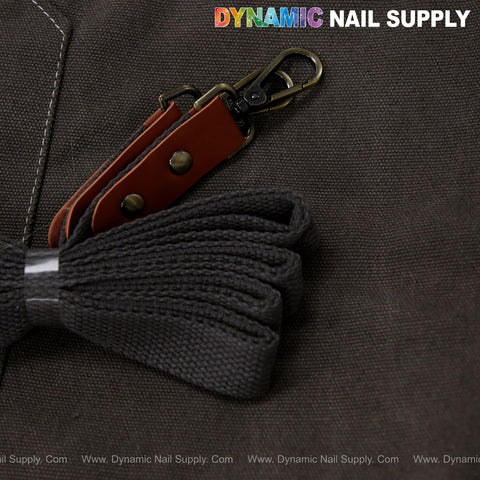 Close-up of Unisex Professional Apron, cotton canvas with brown strap, metal clasp, gray ties. DYNAMIC NAIL SUPPLY text.