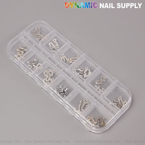 A clear box with 12 compartments holds 24 pcs silver rhinestone zodiac sign nail art charms on a gray background.