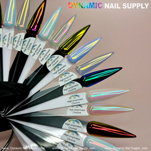 A collection of nail polish samples displays vibrant chrome shades, such as pink, green, blue, and multicolored tones influenced by the Golden/Light-Orange Iridescent Chrome #02 Fine Pigment Powder. Each sample features numbered labels and detailed descriptions. A gloved hand presents the fan of samples, emphasizing Dynamic Nail Supply branding against the pink backdrop.