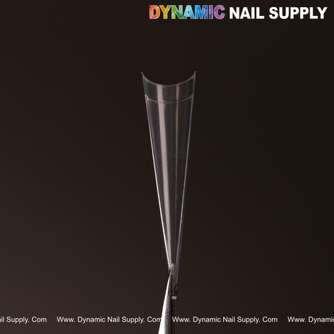 A clear XXL Sharp Stiletto Nail Tip from the 500-pc box, held by tweezers, with DYNAMIC NAIL SUPPLY at top right.