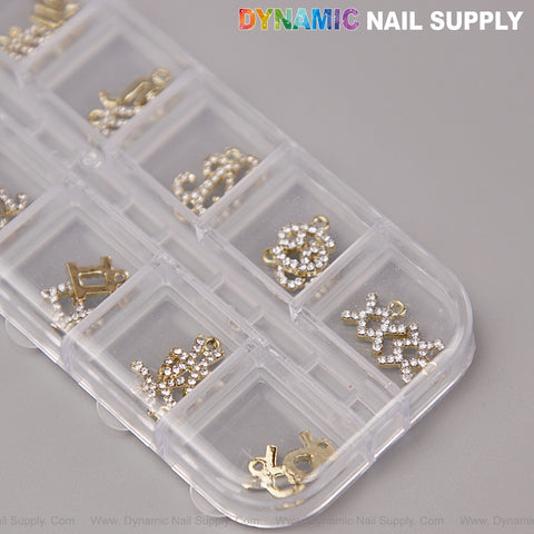 A clear organizer holds 24 Gold & Silver Rhinestone Zodiac Sign Charms for nail art, with Dynamic Nail Supply text above.