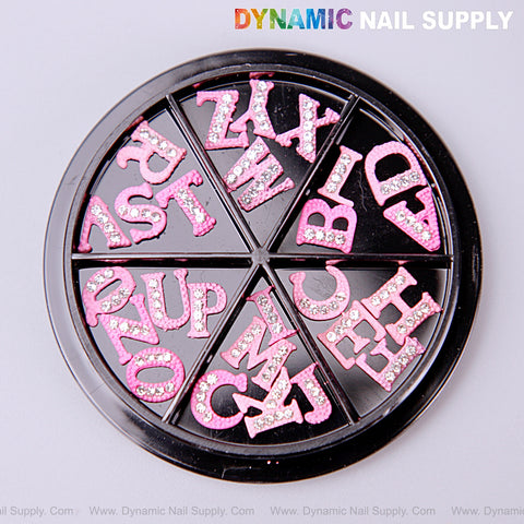 A round tray holds 26pcs pink with silver rhinestone letter nail charms A to Z, each in separate wedge sections.