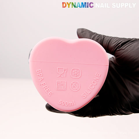 A gloved hand holds a pink, heart-shaped Collapsible Silicone Reusable Bottle labeled “BPA FREE, 500ml.