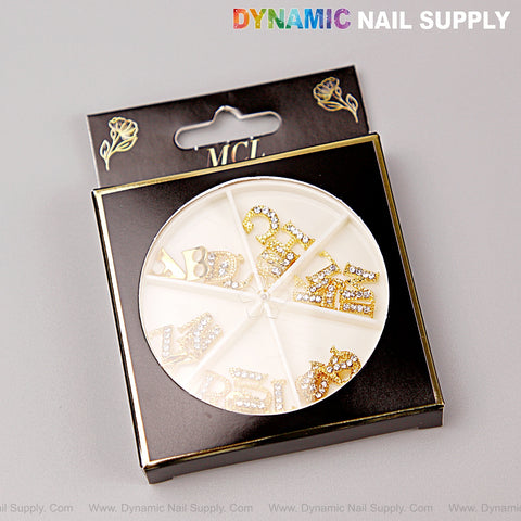 A black case holds 26 gold and silver rhinestone letter nail charms, A-Z, in a round divided tray.
