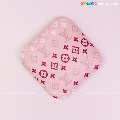 The (RA018) Elbow Armrest is a pink, square cushion with red and white LV-inspired patterns for nail technician support.