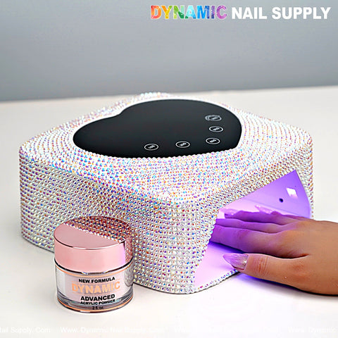 A hand under the AB Big Rhinestone UV/LED Cordless 72W Rechargeable Lamp, acrylic powder jar, and DYNAMIC NAIL SUPPLY logo.