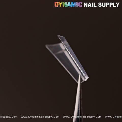A New Short Coffin Nail Tip Half Cover (1 of 600, 12 sizes) held by tweezers with DYNAMIC NAIL SUPPLY in background.