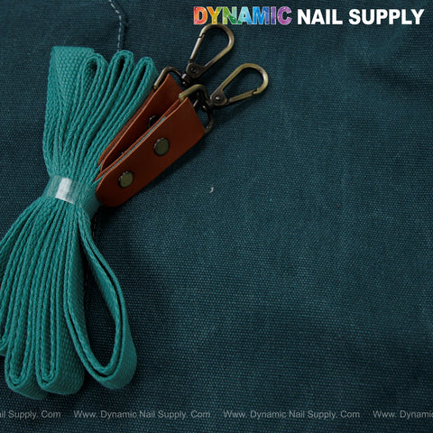 A teal fabric strap for the Unisex Professional Apron with leather ends rests on dark green fabric; logo above.