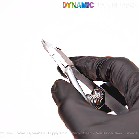 A gloved hand holds NT1217 - G02 5mm Professional Stainless Steel Cuticle Nippers; DYNAMIC NAIL SUPPLY logo at top.