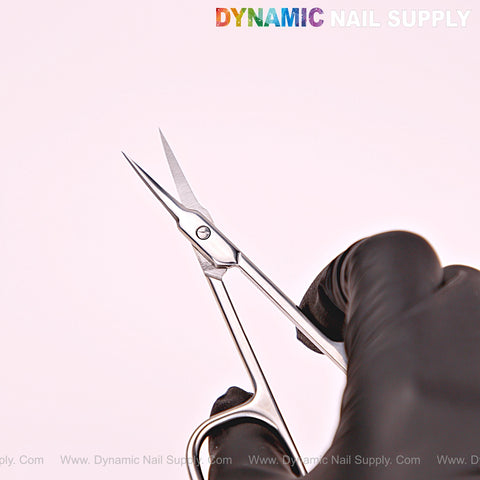 A gloved hand holds NT1215 Silver Premium Curved Tip Cuticle Scissors, stainless steel, logo in top right corner.