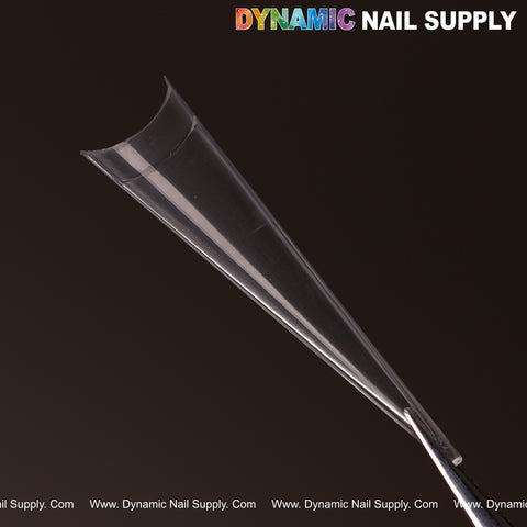 An XXL Sharp Stiletto Nail Tip from a clear box set of 500, held by tweezers; DYNAMIC NAIL SUPPLY top right.