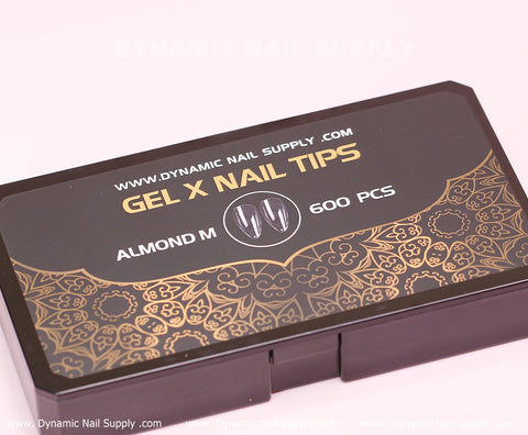 A chic black box with an ornate gold floral pattern and white text displaying www.dynamicnailsupply.com holds 600 pieces of medium-long almond-shaped, full-cover nail tips from Dynamic Nail Supply. Perfect for a sophisticated manicure, these soft Gel X tips are available in ten sizes.