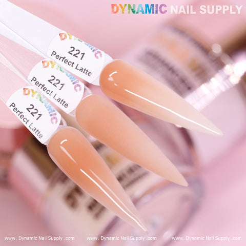 A close-up image features three swatches labeled Perfect Latte - Nude Acrylic Powder (#221), each displaying a glossy, nude-pink shade. These non-toxic swatches are set against a blurred backdrop of nail polish bottles. The brand name Dynamic Nail Supply is visible on both the top and bottom edges of the image.