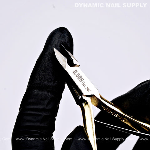 A gloved hand holds D555 Professional Cuticle Nippers with high-tension spring and full jaw for easy trimming.