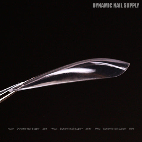 A Sculpted Stiletto XL Full Cover Soft-Gel Nail Tip held by tweezers, black background, branding above.