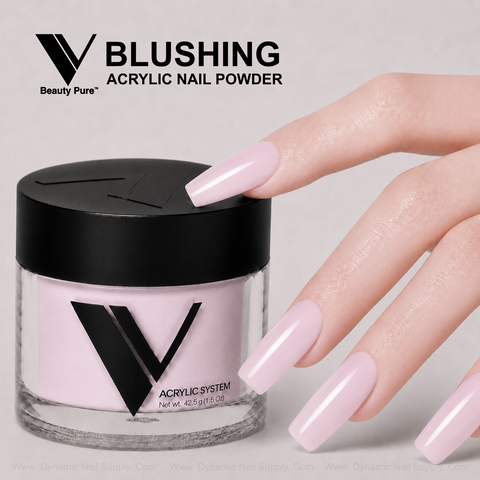 A hand with long, glossy pale pink nails rests beside a jar of V Beauty Pure - Blushing Acrylic Powder.