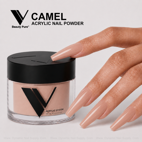 A hand with long nude acrylics holds a V Beauty Pure - Camel Acrylic Powder jar against a plain background.