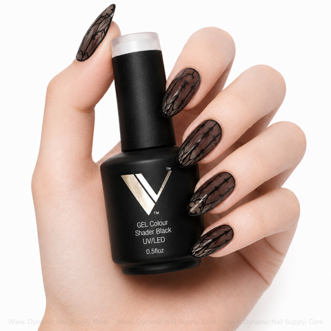 A hand with long, lace nails holds V Beauty Pure Shader Black Gel Polish—perfect for pros and stunning nail art.