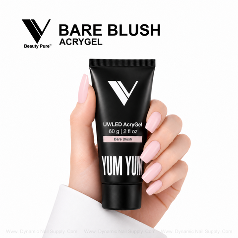 A hand with nude pink nails holds a black Bare Blush - V Beauty Pure AcryGel tube against a white background.