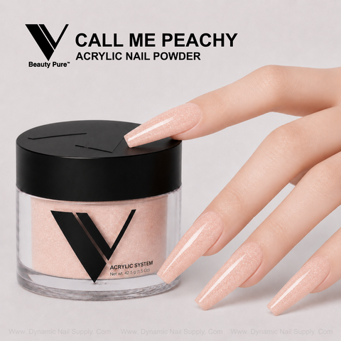 A hand with long peach nails holds a V Beauty Pure - Call Me Peachy Glittery Acrylic Powder jar.