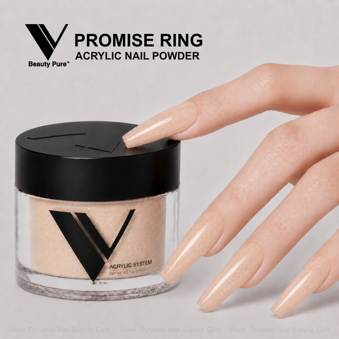 A hand with long, shiny nude nails points to a jar of V Beauty Pure - Promise Ring Acrylic Powder.