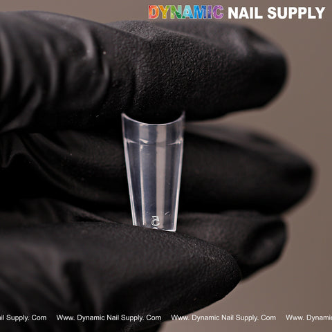 A gloved hand holds a clear short coffin nail tip labeled 2 from the New Short Coffin Nail Tips Half Cover set.