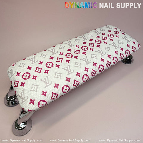 The White Pink LV Pattern ArmRest with Leather Pillow Cushion for Manicure Nails Service from Dynamic Nail Supply is a space-saving armrest featuring stylish red and pink geometric and floral designs similar to designer motifs. Supported by four chrome legs, it's perfect for enhancing any manicure service. The light pink background displays "DYNAMIC NAIL SUPPLY" in the corner of the image.