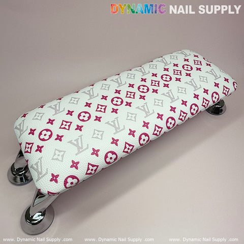 Introducing the Dynamic Nail Supply ArmRest, featuring a rectangular design with a chic pattern of red and gray letters and symbols on a white background. This manicure nails service armrest comes with chrome legs for an efficient use of space and is topped with vibrant "Dynamic Nail Supply" text on a neutral surface.