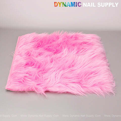 A Hot Pink Faux Fur Fabrics Square Display Mat for jewelry photo props lies flat on a gray surface.