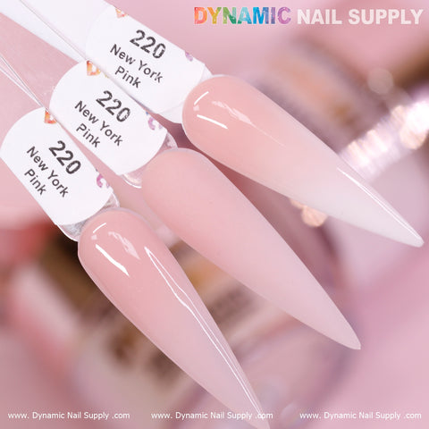 Close-up image of three long, pointed nail tips featuring Dynamic Nail Supply's New York Pink - Nude Acrylic Powder, labeled as #220. The glossy, light pink finish suggests their durability, ideal for daily wear. The brand's logo is displayed prominently at the top of the image against a blurred backdrop of other nail supplies. Visit www.DynamicNailSupply.com for more information.