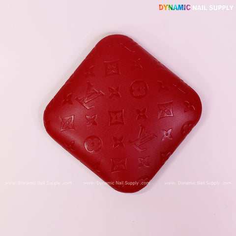 Red LV Engrave Elbow Pad for Nail Tech: soft PU leather, supportive, embossed pattern; Dynamic Nail Supply logo.