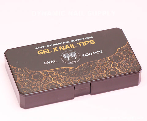 A rectangular black box labeled "Dynamic Nail Supply" contains 600 oval, matte Soft Gel X tips in regular length, available in 11 sizes. The lid features gold floral designs along with the URL www.dynamicnailsupply.com.