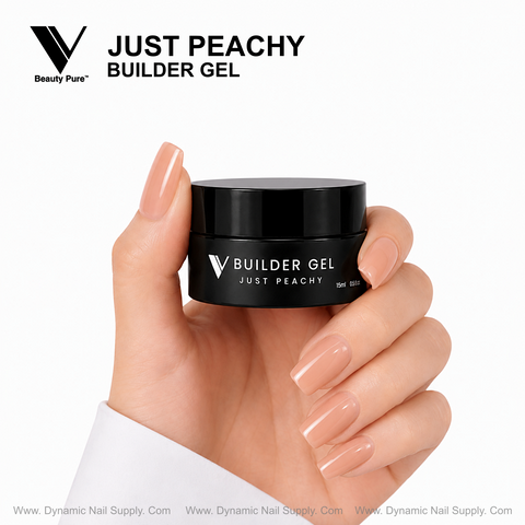 A hand with peachy nude nails holds a Just Peachy - V Beauty Pure Builder Gel jar by Dynamic Nail Supply.