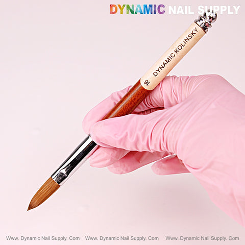 A pink-gloved hand holds the [Crimped] Size 16 Dynamic Kolinsky Brush—100% Pure Kolinsky Hair for acrylic nails.