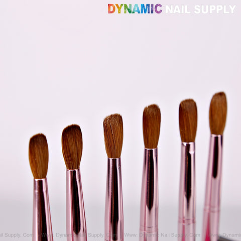 Six Dynamic Metallic Pink Kolinsky brushes for acrylic nails are lined up below the “DYNAMIC NAIL SUPPLY” logo.