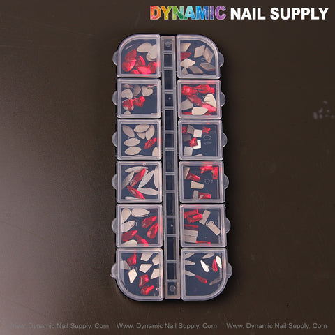 Ruby Red 3 set: 12 compartments of mixed shape nail rhinestone gems (raindrop, square, heart, moon) on dark surface.