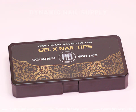 A sophisticated black rectangular box of Dynamic Nail Supply's [Square M] Full Cover Tips, designed for medium square matte tips, holds 600 soft gel x tips in 11 sizes. The lid features an elegant gold floral pattern with the company’s website displayed above.