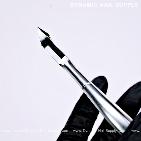 A black-gloved hand holds the D506 Carbon Steel Cuticle Nippers with angled tip against a white background.