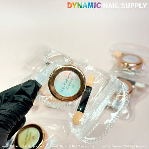 The image displays a gloved hand holding a small cosmetic jar with a rose-gold lid labeled Iridescent Chrome #08, featuring light-green and purple mermaid pigments known for their high brightness. The jar is enclosed in a clear plastic bag along with a nail applicator. Two additional jars are visible in the background, beneath the brand name Dynamic Nail Supply.