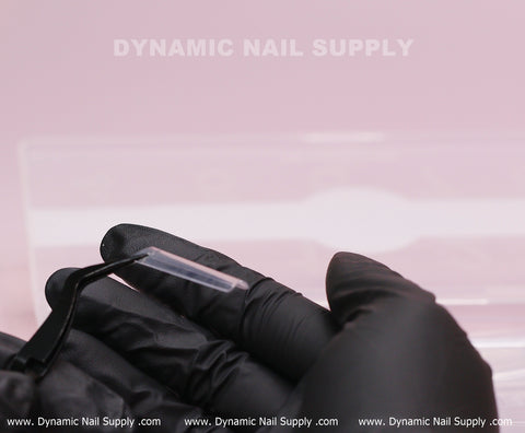 A gloved hand holds XL Square Nail Tips—extra long, straight, easy to apply—by DYNAMIC NAIL SUPPLY on pink background.