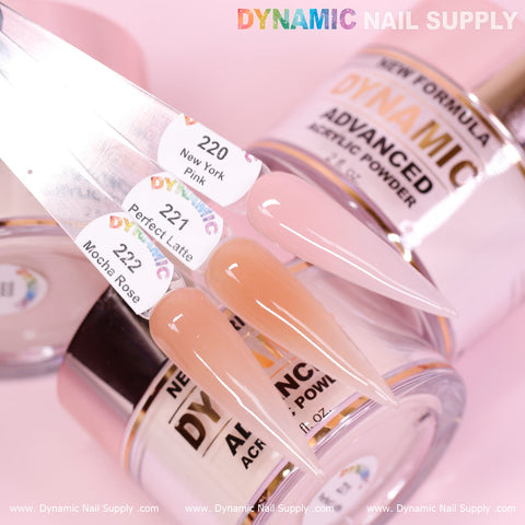 A close-up displays three long, pointed nails adorned with the subtle beauty of Nude Acrylic Powder against jars of Dynamic Advanced Acrylic Powder. These stylish nails, featuring colors labeled 220 New York Pink, 221 Perfect Latte, and 222 Mocha Rose, underscore the superior quality and durability that Dynamic Nail Supply provides for stunning nail designs.