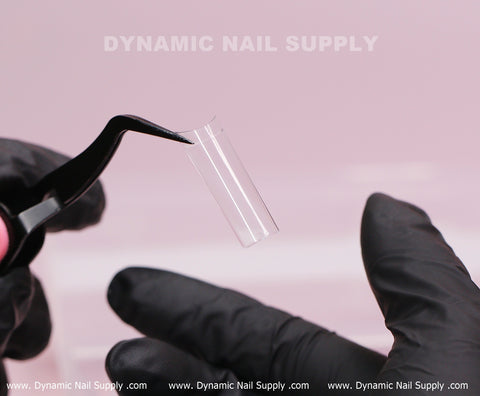 A gloved hand holds XL Square Nail Tips (Not C-Curve) against pink. Text reads Dynamic Nail Supply.
