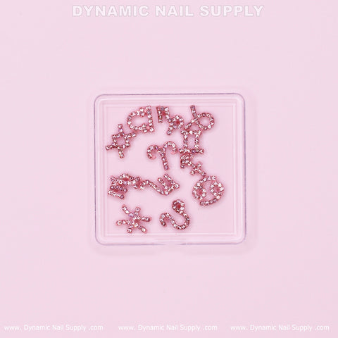 A square container displays the Luxury Light Pink Zodiac Symbol Sign Nails Charm Set with Rhinestone, which includes a variety of pink rhinestone nail charms featuring zodiac symbols, crosses, and stars against a light pink background. The brand name, Dynamic Nail Supply, is prominently displayed at the top and bottom edges.