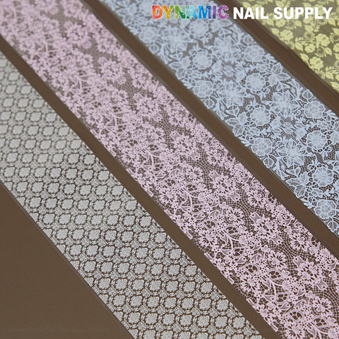 Six strips of Pink Blue White Yellow Mixed Design Nail Foil 6 for delicate nail art, on a brown background.