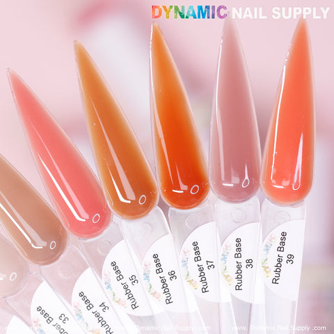 Close-up of six elongated, pointed nail polish swatches, each labeled as part of the (BIAB) Rubber Base gel collection with numbers 35 to 40. The shades vary from a pale pink to a deep terracotta. A subtle pink background highlights the DYNAMIC NAIL SUPPLY brand name prominently displayed at the top in colorful letters.