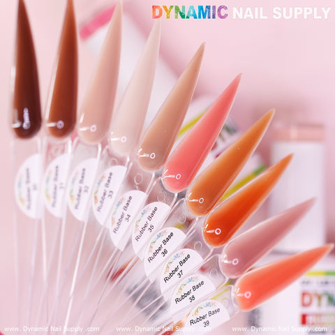 On elongated, clear swatches, a vibrant array of nail color samples from the Dynamic Nail Supply (BIAB) Rubber Base gel collection, numbered 30 to 39, is showcased. The shades vary from dark brown to a spectrum of pinks and nudes. In the background, there's a blurred image that highlights the Dynamic Nail Supply brand logo and website text.